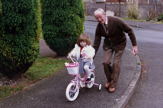 Grandad helping Dominique to ride her bike
