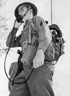 ww2 . british army . signals field radio . kit . metal protectd helmet . black & white photo .