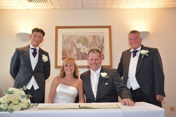 Barb and Justin signing the register on their wedding day, with witnesses Oli and John 