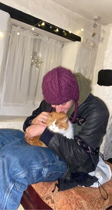 Henry hugging a cat in a funky hat