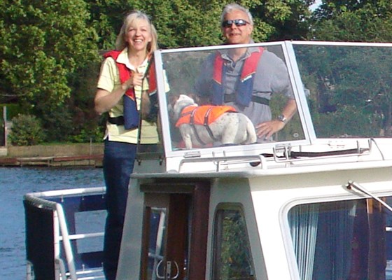 A smiling Liz, Poppy and Geoff on their boat.