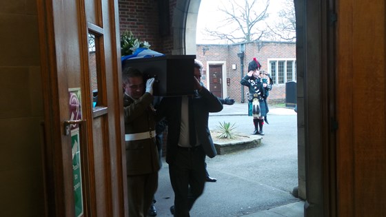 The Piper salutes the entry of the coffin with the Scottish flag draped over