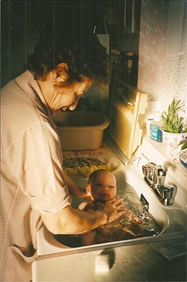Carmela bathing her grandson in the sink.