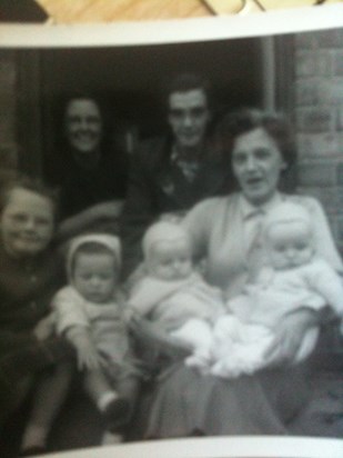 Obviously very young. One of the two babies is Ed, the other Terry (not sure who is who), aunty Mary holding us, mum in background.