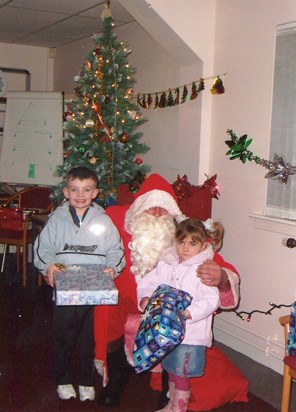 Sean and and lauren recieving their gifts from santa at christmas party .