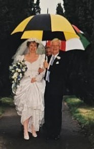 Sharne and Donald walking up the path in the rain on her wedding day - Umbrella fun!