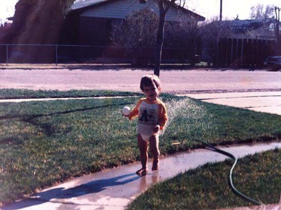 Little Evan playing with a ball in the sprinkler