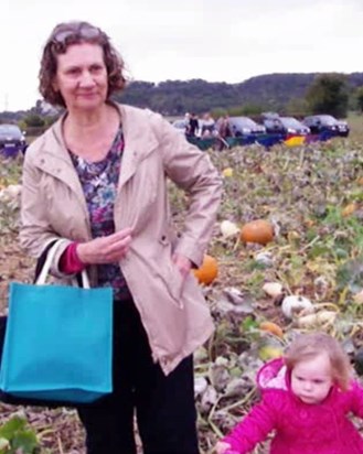 a happy Grandma with little Ava in a pumpkin field close to Halloween