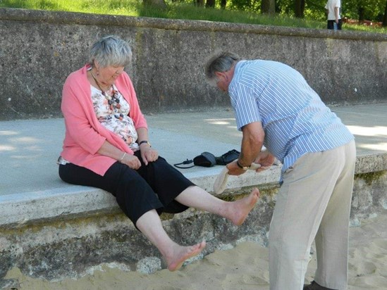 Dad wiping sand from Jennys toes and putting her socks on! 