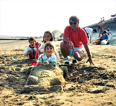 Mike and the kids with one of his sand creations, a Formula One racing car