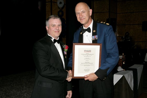 Chris Wight accepts an award from the Commissioner on behalf of Jennie Harvey