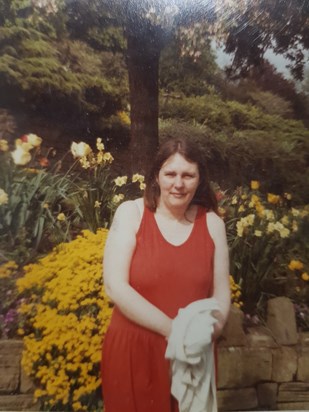 Carol in her younger days posing near her favourite flowers 
