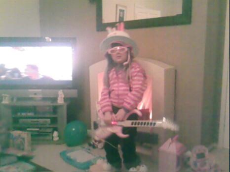 Abbie playing the guitar with a funky hat