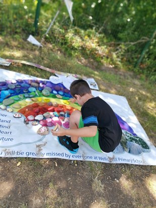 Cathen placing a stone on memorial rainbow 