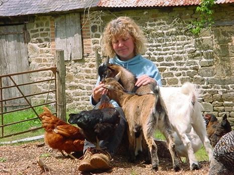 Debbie petting goats and chickens near old barn, July, 2002