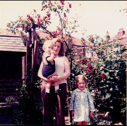 In our garden, Palmer’s Green 1974. That rose pergola behind us had lavender at toddler level and was always full of bees, so we had to bravely whizz through at speed on our tricycles to reach the playhouse!