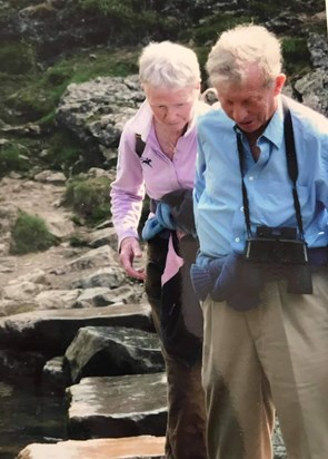 David helping Roseanne over stepping stones across a river